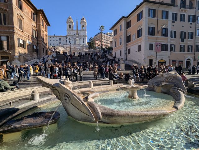 The Spanish Steps in Rome, Italy, a monumental 18th-century staircase connecting the Piazza di Spagna with the Trinità dei Monti church, with tourists ascending and descending the steps.